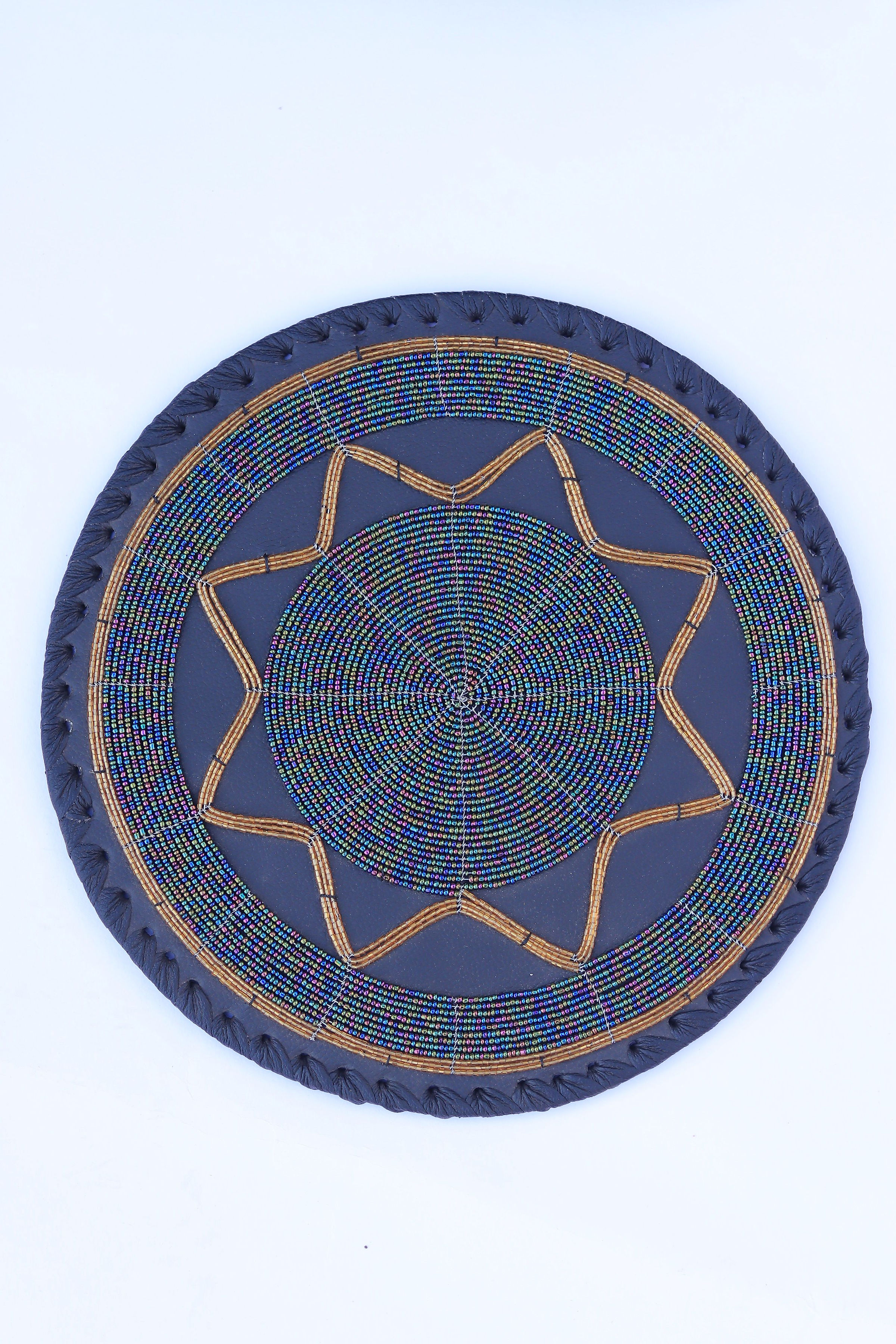 Round beaded place mat with iridescent blue-green beads and gold star motif on dark leather
