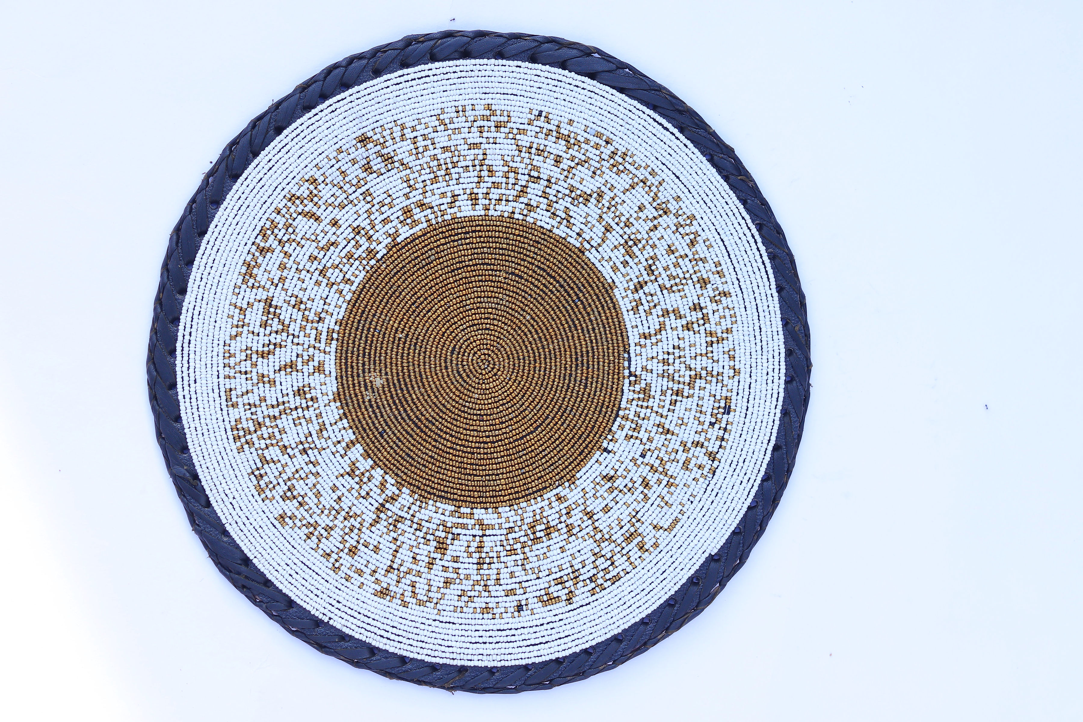 Round beaded place mat with ivory and copper-gold concentric beading and navy braided edge