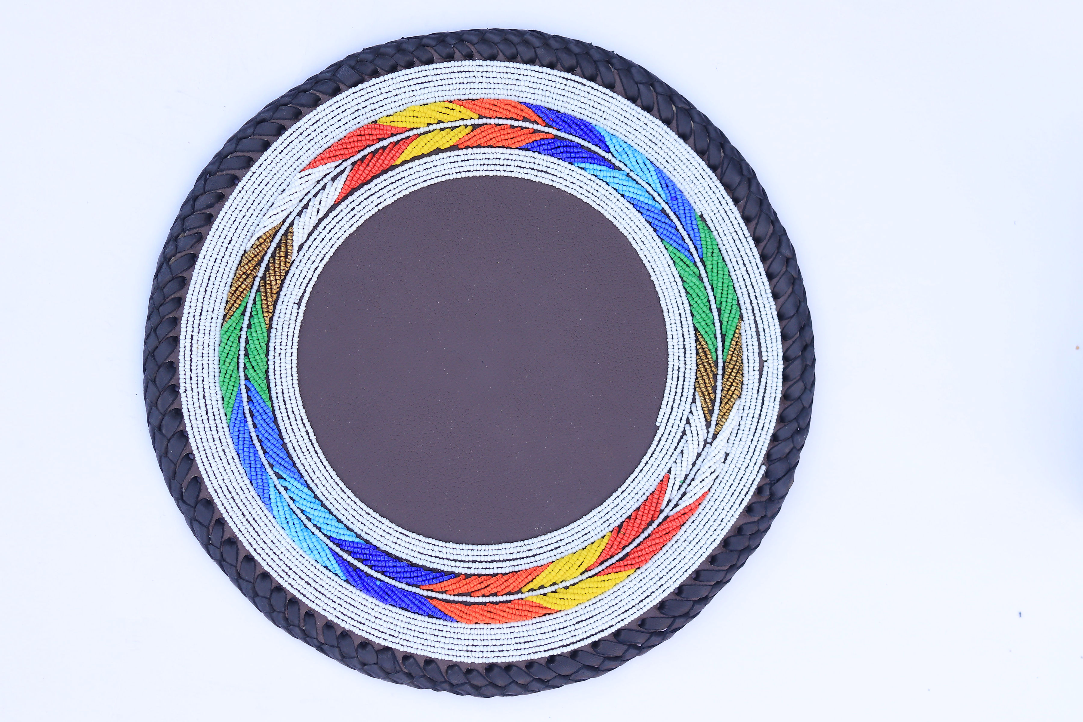 Round beaded place mat with white base and rainbow feather border on brown leather